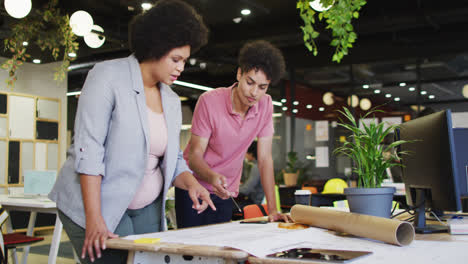 feliz gente de negocios biracial discutiendo trabajo con esquema en la oficina