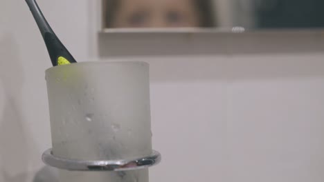 girl brushes teeth in bathroom focus on holder with brush