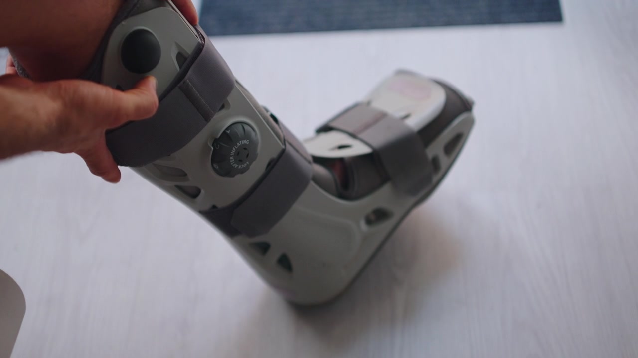 Person Adjusting Medical Orthopedic Walking Boot on Injured Leg