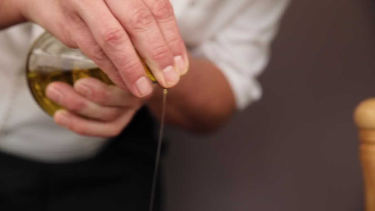 шеф-повар наливает оливковое масло