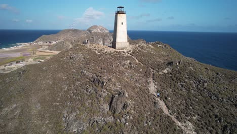 una mujer sube la colina para llegar al faro histórico de gran roque en un día despejado.