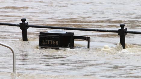 fast flowing flood water covering railings and litter bin at bewdley, worcestershire