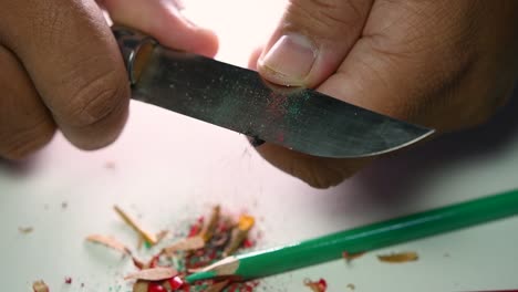 Footage-of-hands-slowly-sharpening-a-pencil-and-some-coloured-pencils-with-a-sharp-knife