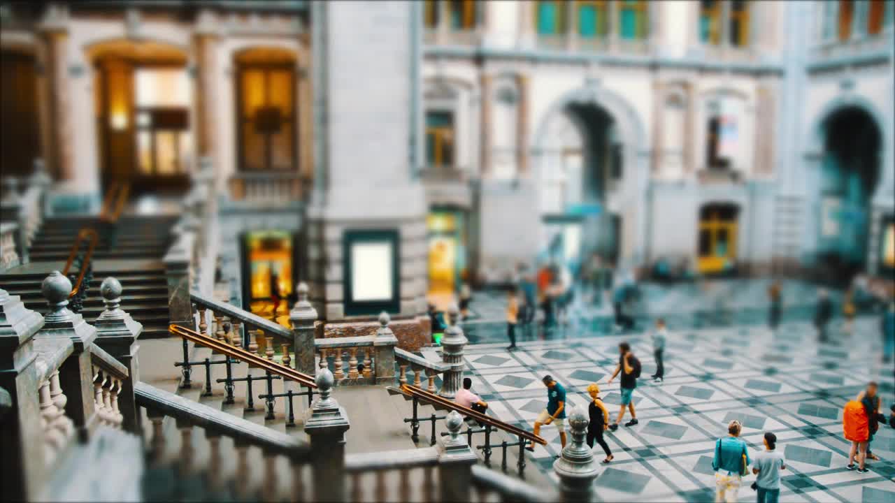 A tilt-shift time lapse of people in a beautiful train station.