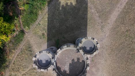 aerial top-down drone shot above grass, showing shadows of blaise castle’s turrets. as the drone pulls back, the historic castle emerges from the shadow
