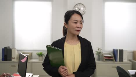 closeup portrait of happy asian female manager nodding head while walking toward camera checking if workers are doing their duties in office. successful leadership concept