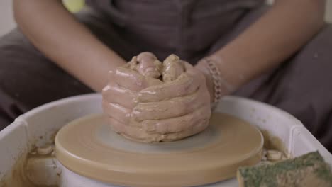 folk potter pushes thumbs into wet clay to skilfully create earthenware close-up