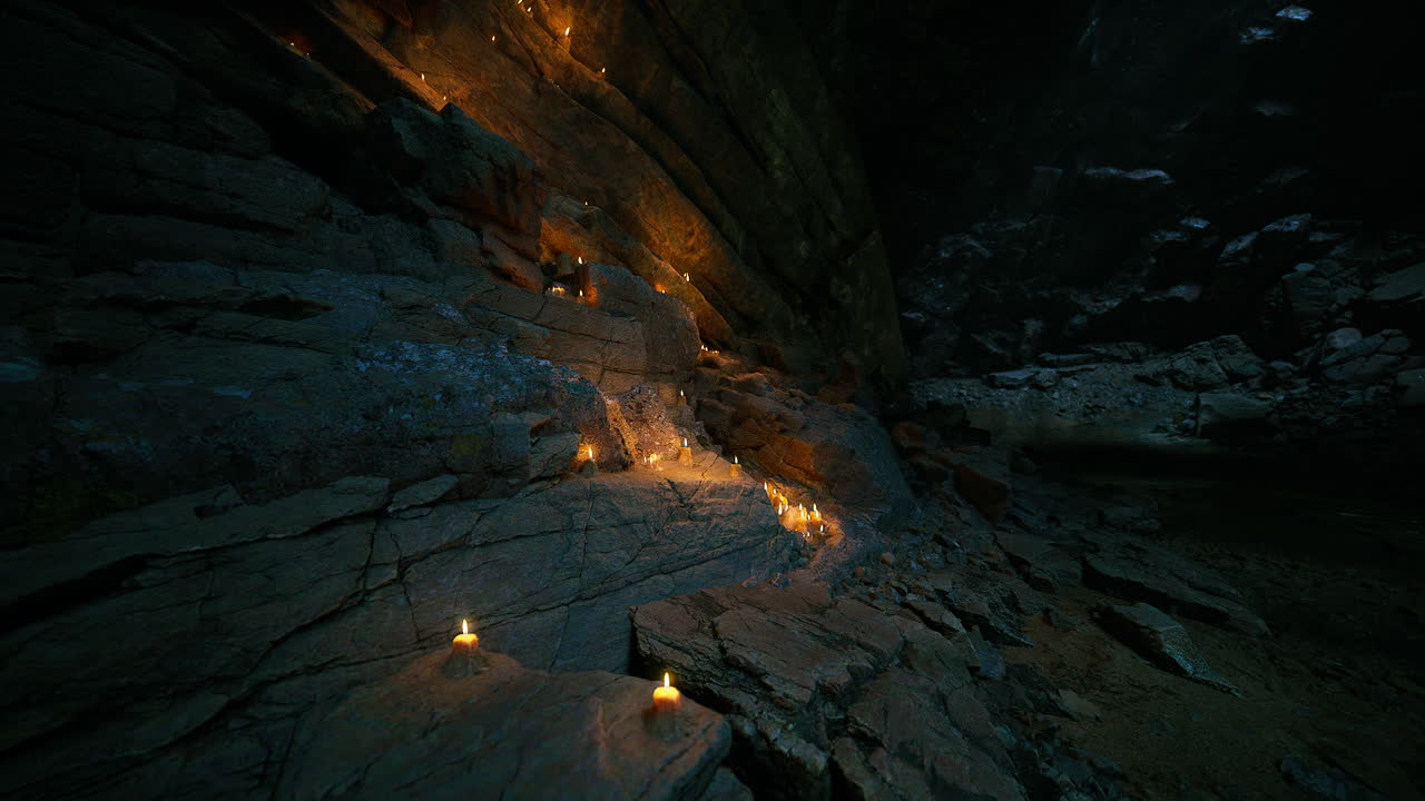 Candles illuminate rocky cave interior at dusk in tranquil setting
