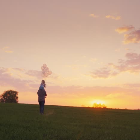 father carries his daughter with balls across the field at sunset