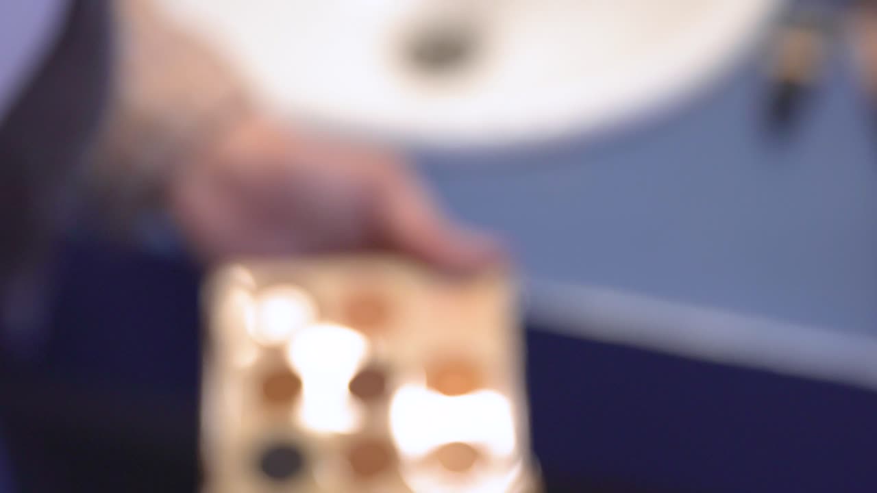 메이크업 아티스트가 브러쉬로 모델의 얼굴에 아이도우를 적용합니다.