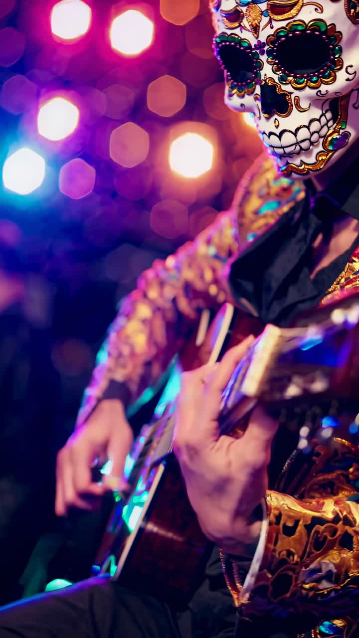 Inquadratura dal basso di un musicista con abiti vivaci e trucco da teschio messicano che suona la chitarra.