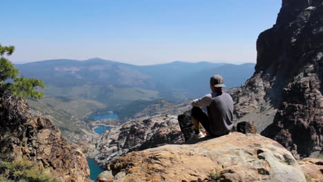 Junger-Mann-Sitzt-Oben-Auf-Dem-Berg-Und-Blickt-Auf-Den-Malerischen-See-In-Der-Sierra-Nevada-In-Der-Nähe-Von-Lake-Tahoe,-Kalifornien