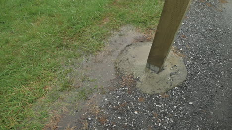 slow motion rain drops falling to the ground next to a wooden beam in cement, belonging to a house