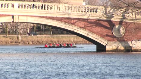 longshot of the harvard university rowing team passing under a bridge over the charles rives near cambridge massachusetts