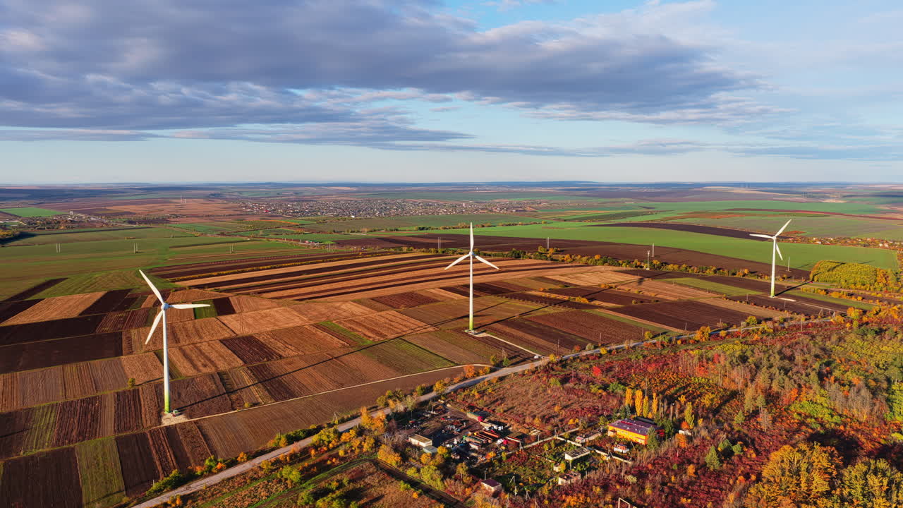 Aerial drone view of several wind turbines placed across Moldovan farmlands under a bright blue sky