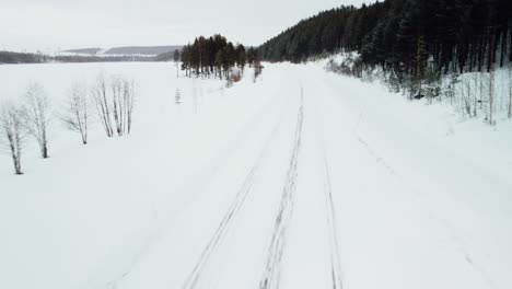 snow-covered-road-with-a-beautiful-view-of-the-mountains-in-the-background-of-the-Arctic-Circle-from-the-drone