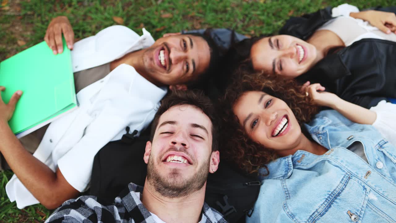 Jovens adultos diversos felizes deitados na grama tirando uma selfie