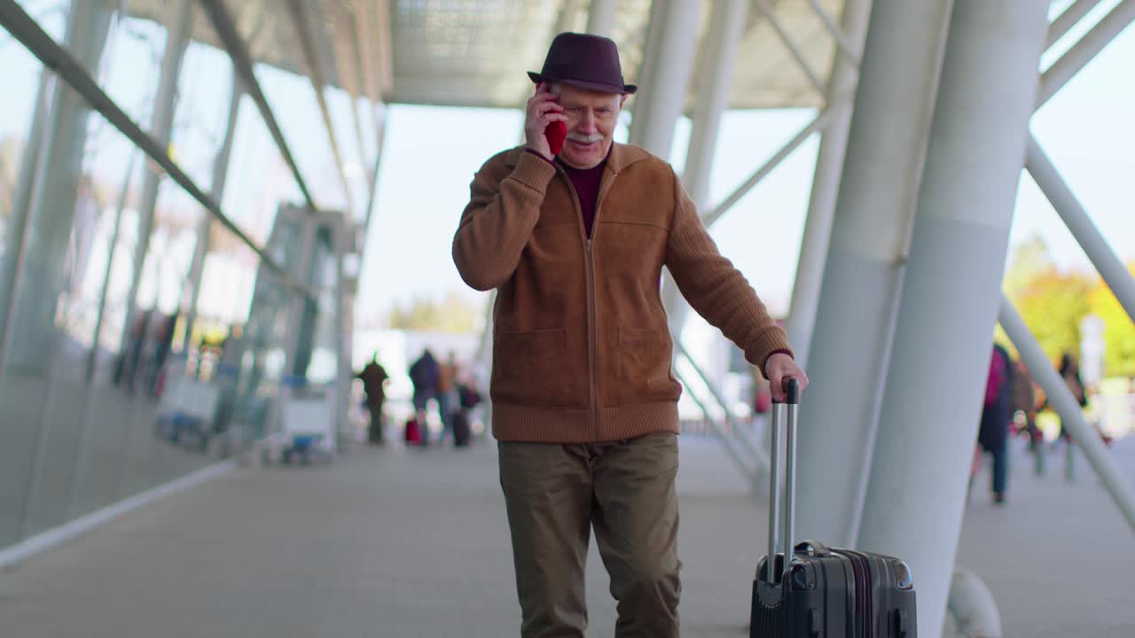 anciano hombre de abuelo turista caminando en la sala del aeropuerto internacional usando una conversación por teléfono móvil