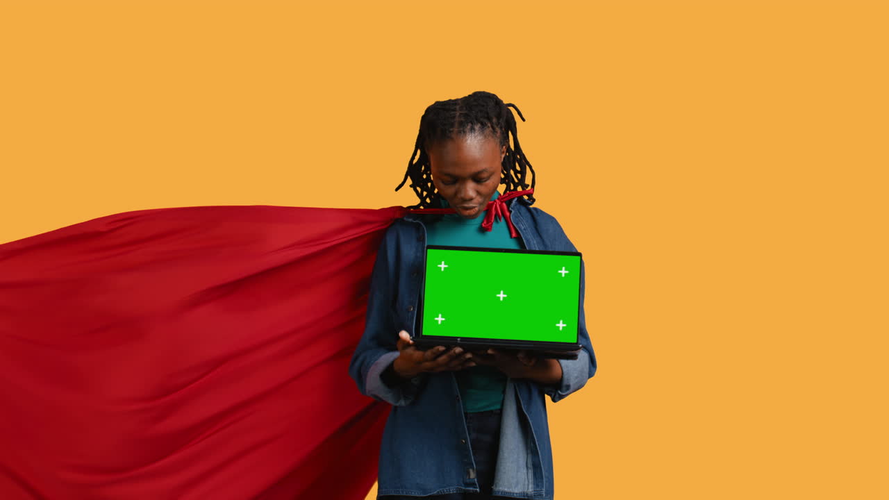Woman posing as hero showing chroma key laptop, studio background