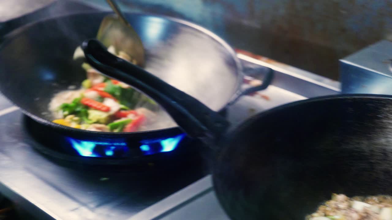 imágenes cinematográficas de cocina de 4k de un chef tailandés cocinando comida tailandesa en un wok en la cocina de un restaurante en tailandia