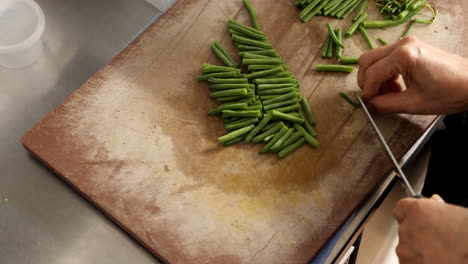 Slow-motion,-circle-pan-and-top-view-the-movement-of-Asian-chef-cutting-green-bean-in-the-kitchen