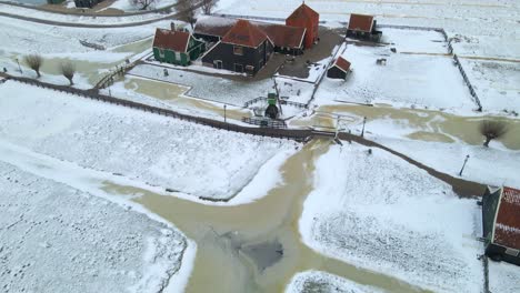 Traditional-Dutch-landscape-with-farm-and-iconic-windmills-near-river-in-winter