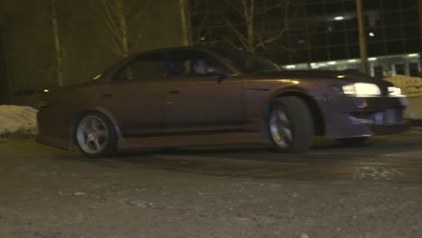 coche a la deriva por la noche en la ciudad nevada