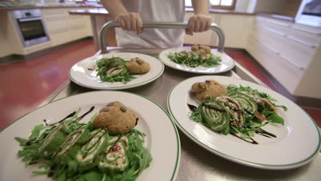 meals moving through restaurant kitchen on steel cart, pushed by kitchen assistant