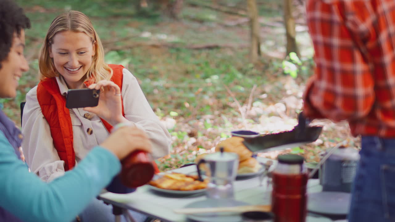 캠핑 휴가 에 있는 여자 친구 들 이 텐트 에 의해 식사 를 먹는 것 처럼 드폰 으로 음식 의 사진 을 찍는 여자