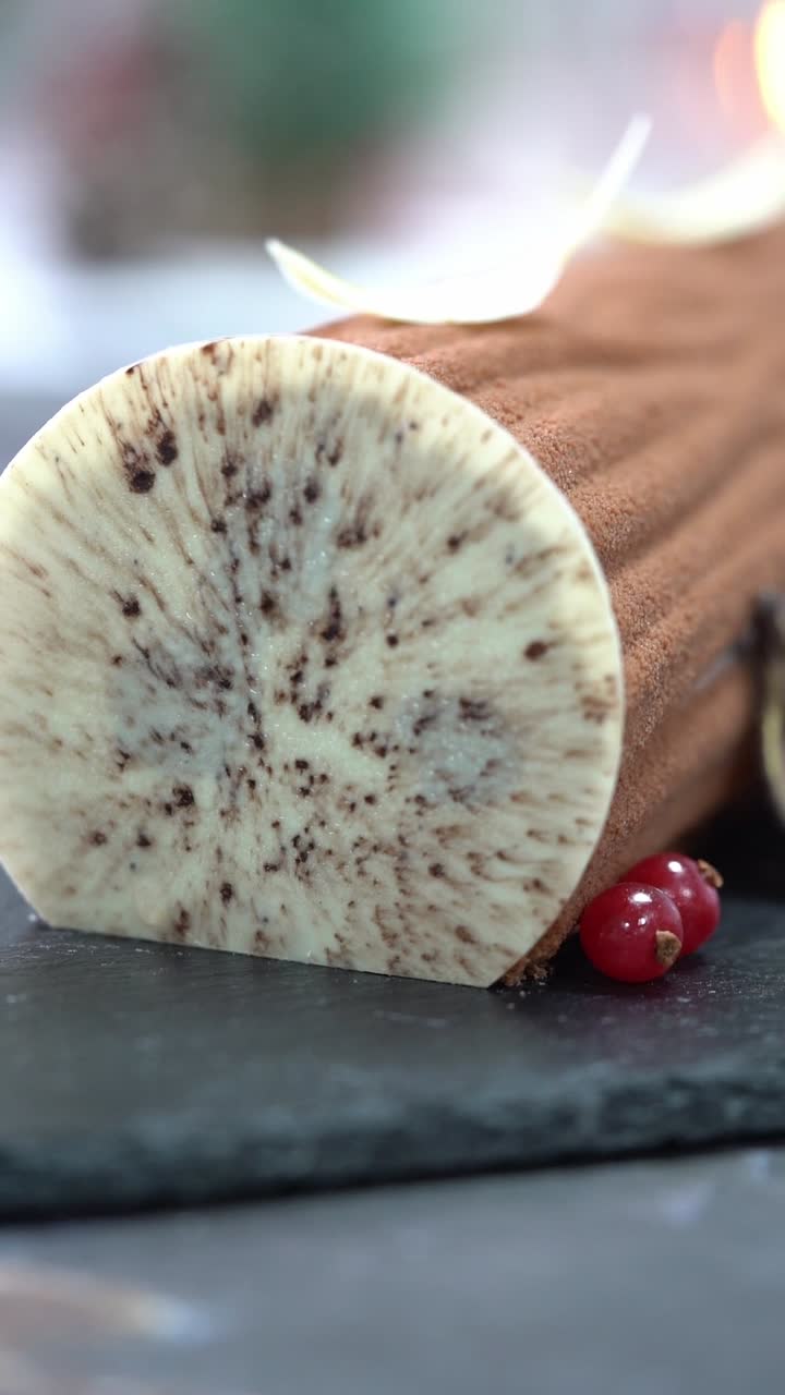 Uno chef decora un tronchetto di cioccolato con ciliegia, copertura al cacao texturizzata e dettagli decorativi a forma di foglia, inquadratura ravvicinata, inquadratura di dettaglio