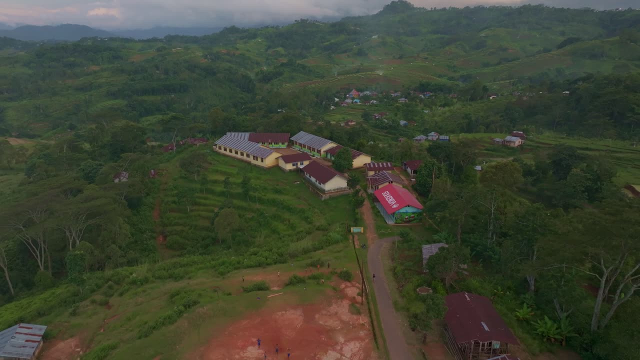 Landlig gade med børn på fodboldbane og skyggefulde træer, Flores, Indonesien