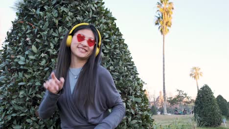 happy asian woman having fun while listening to music and dancing outdoors in the city street.