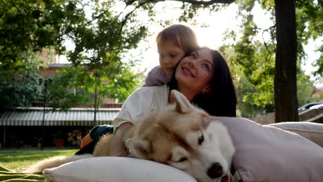 familia y mascota, joven madre con niño yace cerca de perro husky en el fondo de la naturaleza de primer plano