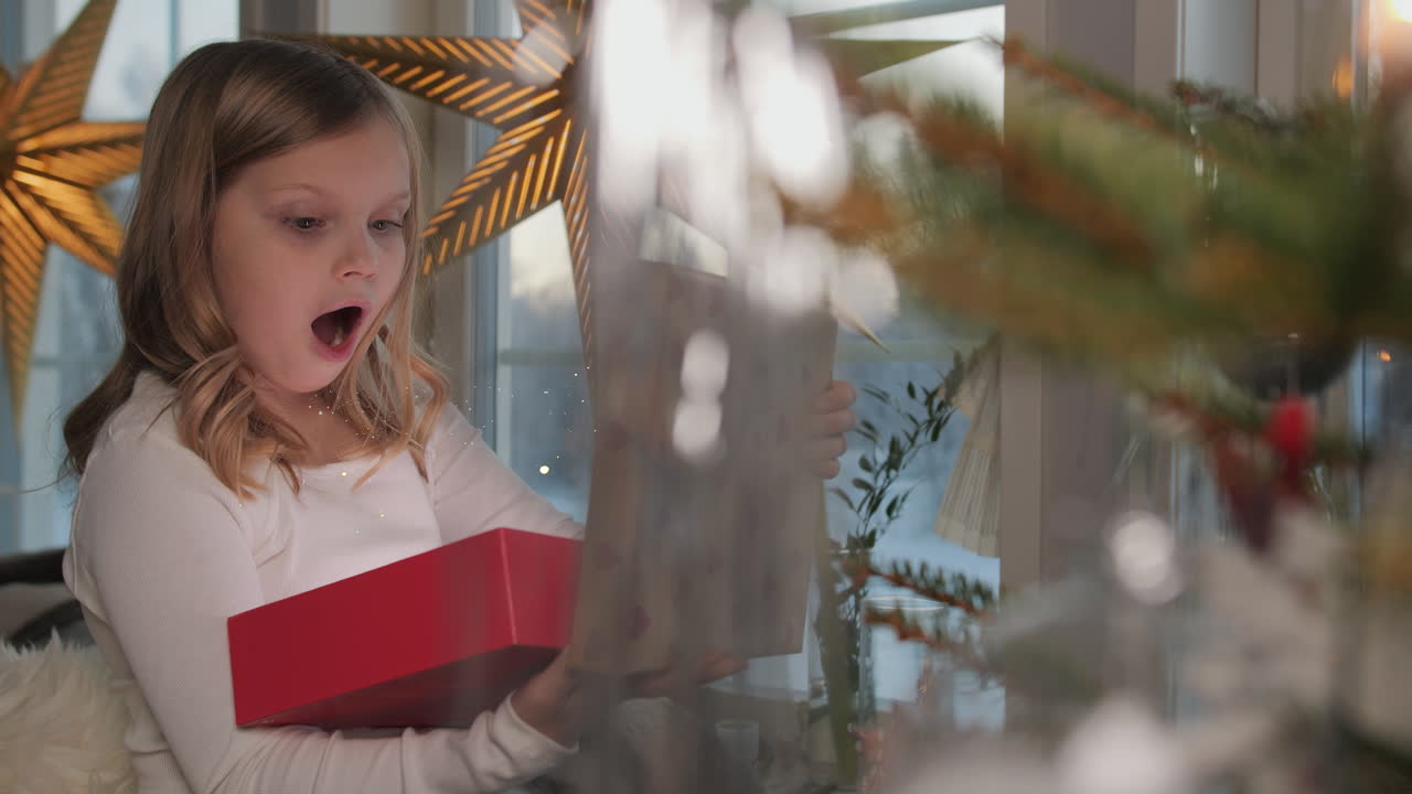 젊은 금발 소녀는 마법의 반이는 크리스마스 선물을 열립니다.