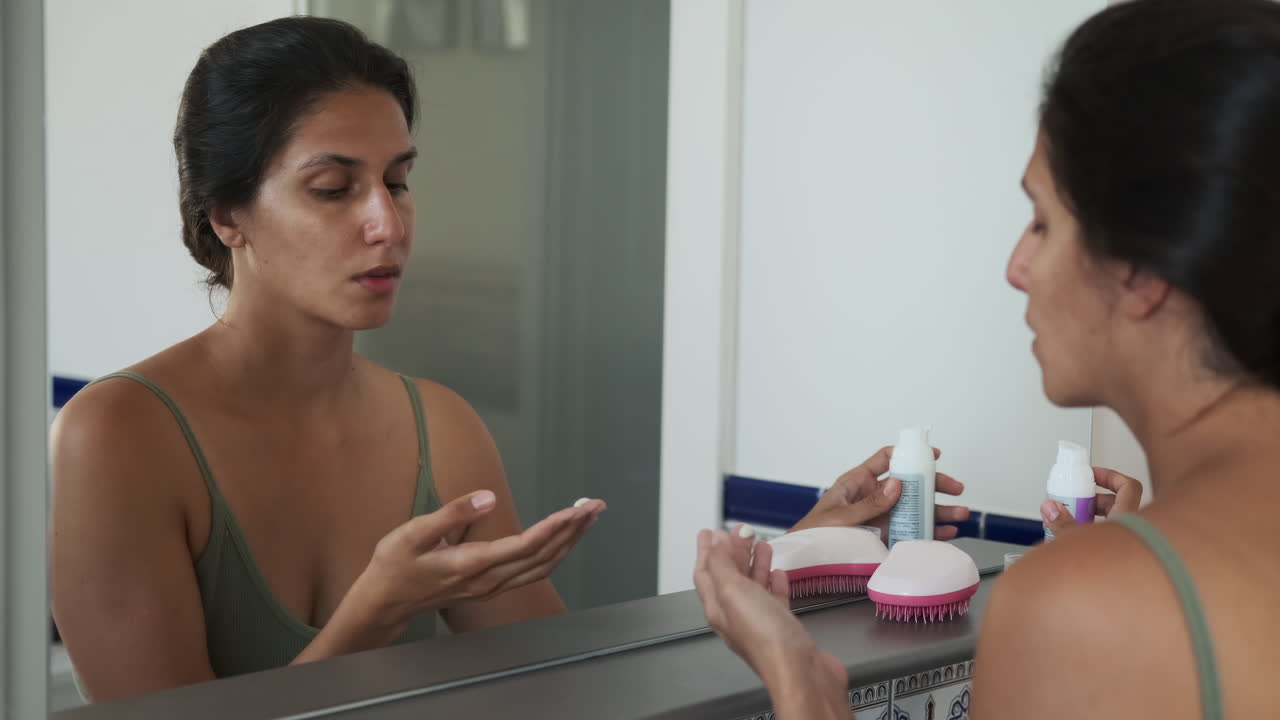 mujer aplicando crema para la cara en el baño