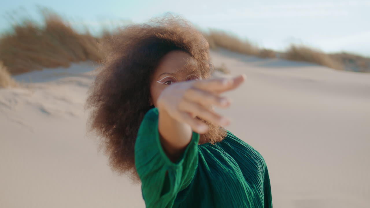 유연한 여성이 모래 언덕을 가까이에서 춤을 춘다. 여자 댄서가 몸을 유혹적으로 구부린다.