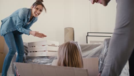 Father-pushing-little-girl-in-paper-box-while-moving-house.