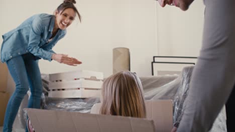 Father pushing little girl in paper box while moving house.