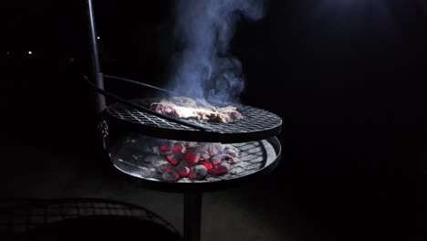 barbacoa rústica carne a la parrilla en fuego abierto carbón al aire libre por la noche en cámara lenta