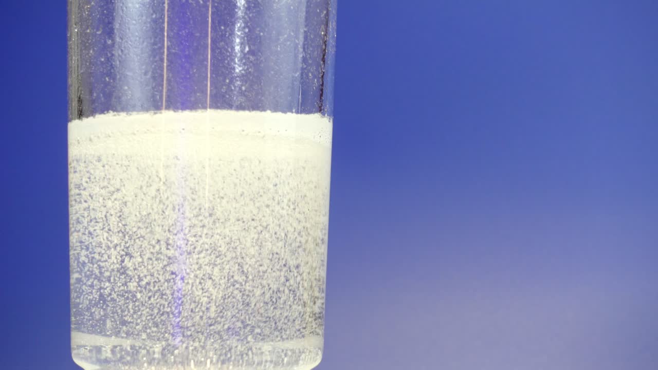 Effervescent powder dissolving in water against a blue background