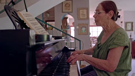 anciana tocando un piano de cola en su casa