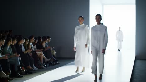 a dramatic fashion show unfolds with models gracefully treading the runway in elegant white attire, capturing the essence of contemporary style and artistic expression