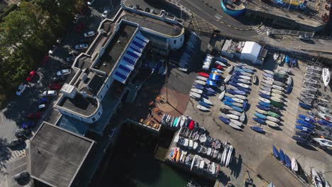 royal st. george yacht club, dún laoghaire, county dublin, ireland, september 2024. drone high angle bird's eye view orbits above sail boats and yachts pulling back to reveal the seafront.