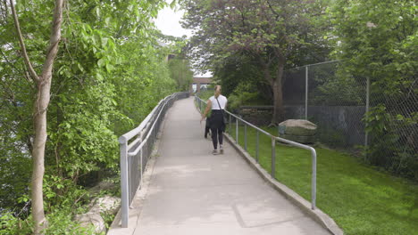 wide shot of a young woman walking her dog down a path with lots of leaves in an urban environment