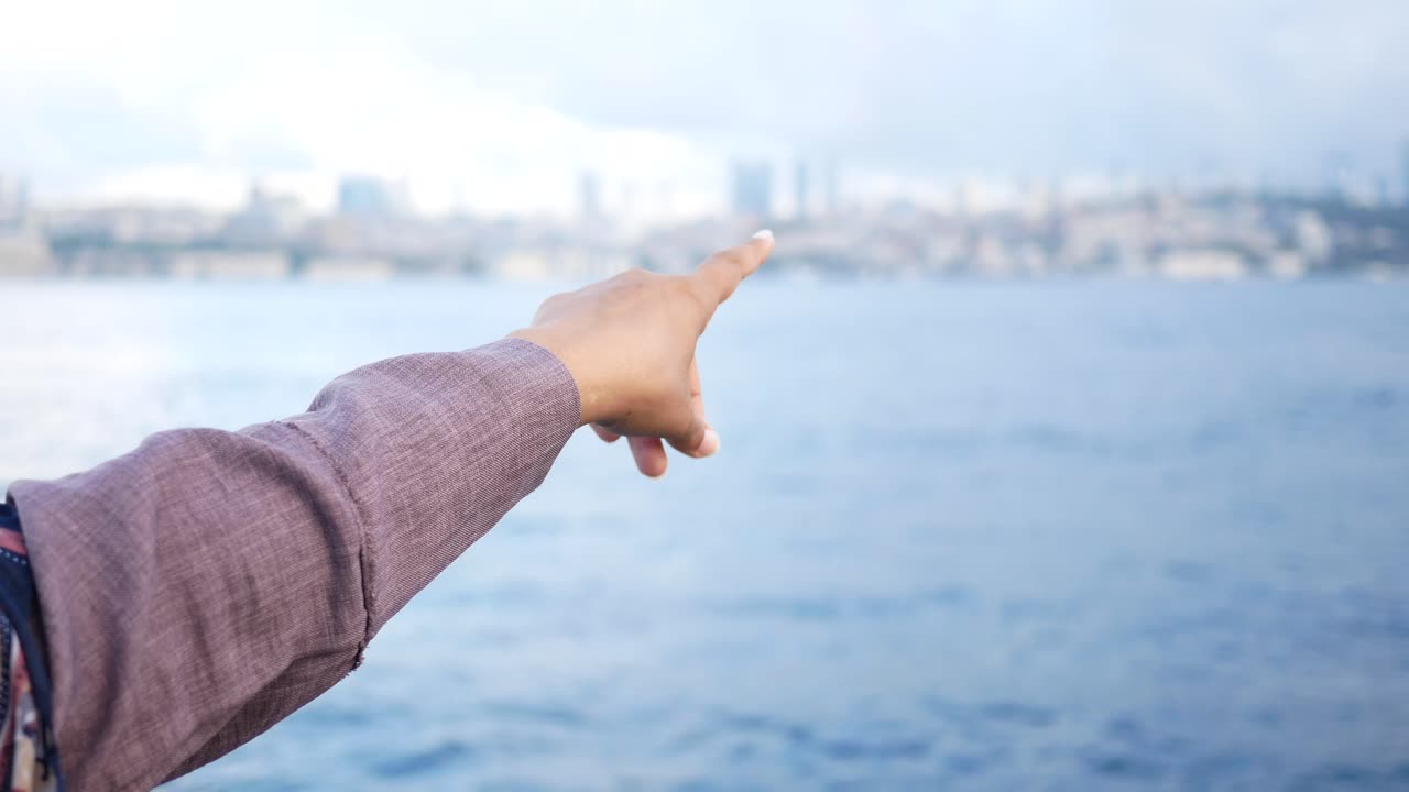 한 사람 이 도시 를 향해 물 을 향해 손가락 을 가리키고 있다