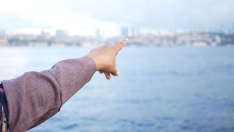 una persona señala con el dedo el agua hacia una ciudad