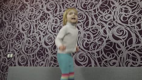 little happy child jumping and dancing on sofa and listening music. slow motion