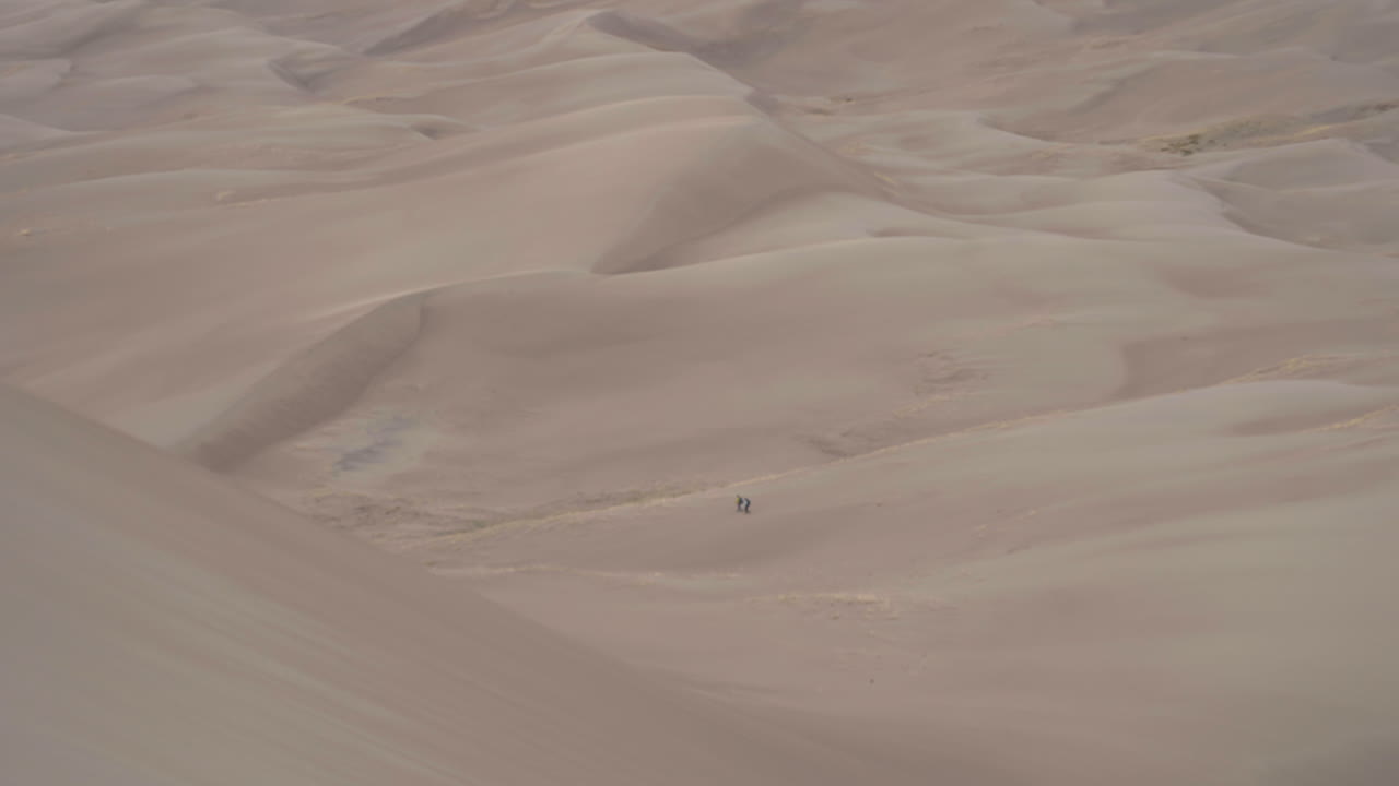 excursionistas que atraviesan un enorme campo de dunas de arena en el gran parque nacional de las dunas de arena