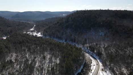 Rising-perspective-of-winding-road-and-river-among-rural-hills-during-winter-season