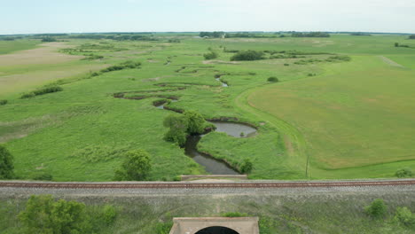 Aerial-view-of-creek-running-under-rail-road-tracks-in-a-remote-area-of-Minnesota